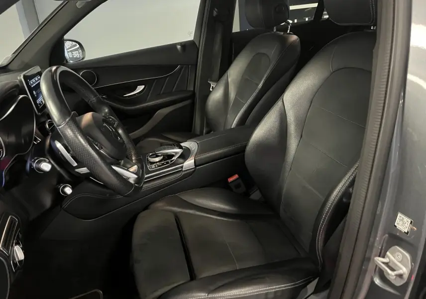 Vue intérieure côté conducteur du Mercedes GLC 220 d Sportline gris avec sièges cuir noir et volant multifonctions.