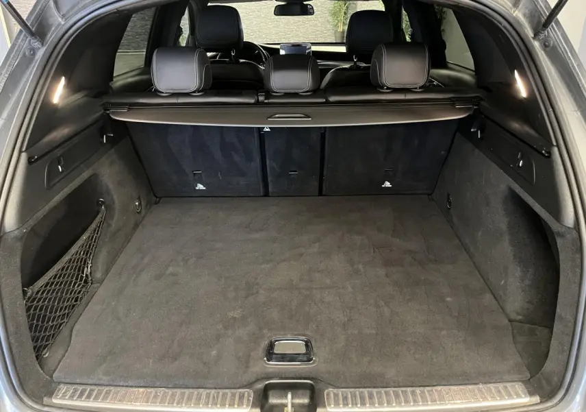 Coffre spacieux ouvert du Mercedes GLC 220 d Sportline gris, intérieur noir avec filet latéral et cache-bagages.