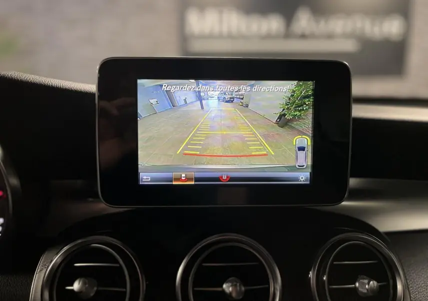 Écran central montrant la caméra de recul du Mercedes GLC 220 d Sportline gris, intérieur noir avec aérateurs ronds.