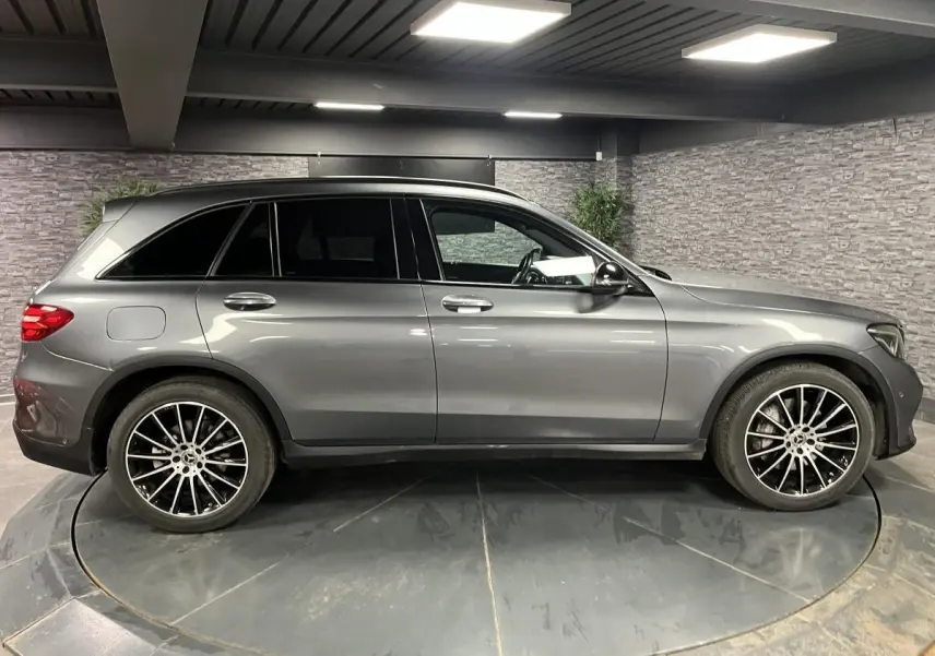 Profil droit d'un Mercedes GLC gris métallisé avec jantes AMG 20 pouces multibranches dans un garage.