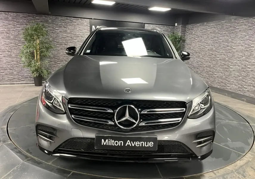 Mercedes GLC 220 d Sportline gris métallisé vu de face, avec calandre AMG et phares LED allumés.