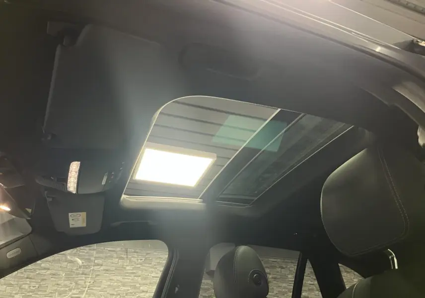 Toit ouvrant panoramique en verre vu de l'intérieur sur un Mercedes GLC gris, avec sièges en cuir noir.