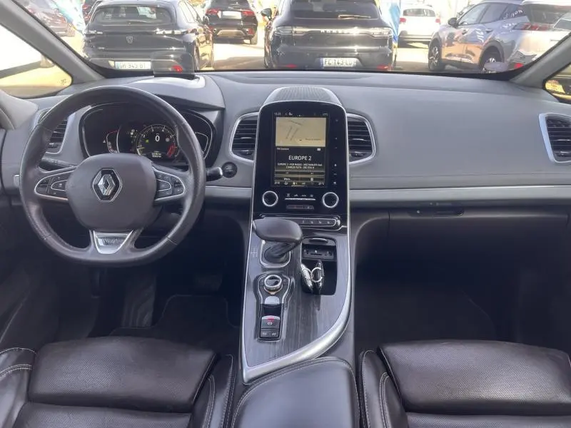 Vue intérieure frontale du tableau de bord et console centrale du Renault Espace gris Cassiopée avec écran tactile et volant cuir multifonction.