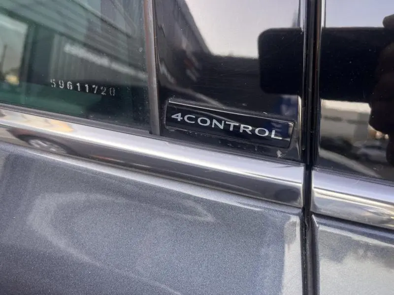 Gros plan sur l’emblème 4CONTROL sur la porte arrière droite d’un Renault Espace gris Cassiopée.