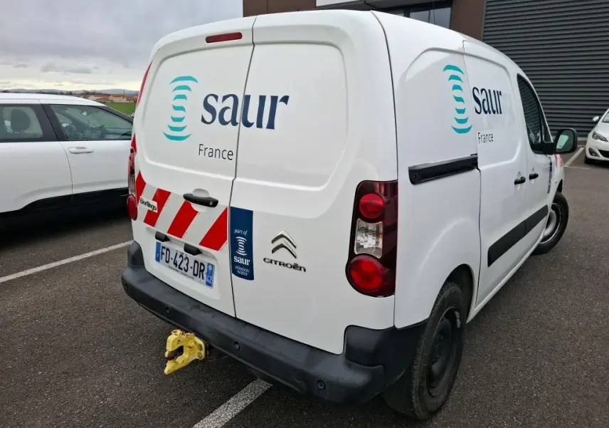 Vue 3/4 arrière droite d’un utilitaire Citroën Berlingo blanc avec logo Saur et marquages rouges sur porte arrière.