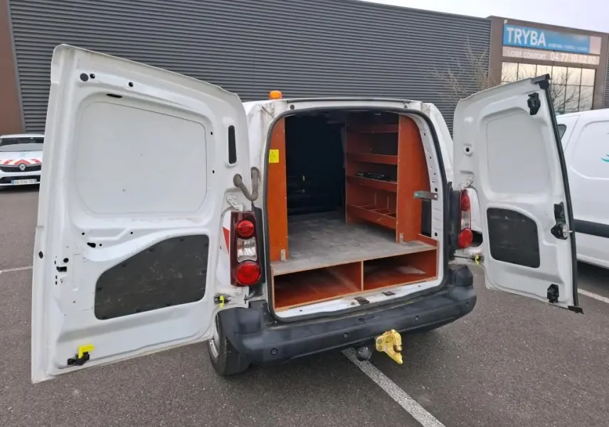 Vue arrière d’un Citroën Berlingo blanc 2019 avec portes ouvertes et étagères en bois dans la zone de chargement.