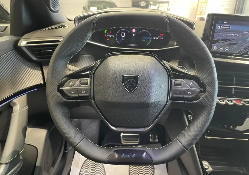 Vue centrée sur le volant cuir noir avec logo Peugeot et badge GT, tableau de bord digital et écran tactile gris du Peugeot 2008.