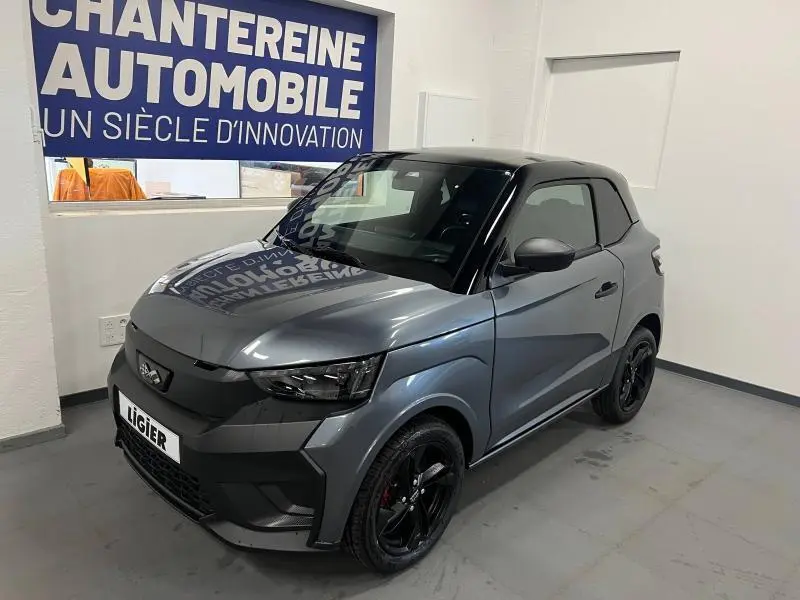 Vue 3/4 avant d'une Ligier JS50 Sport Elite E5+ gris métallisé avec toit noir et jantes noires dans un showroom.