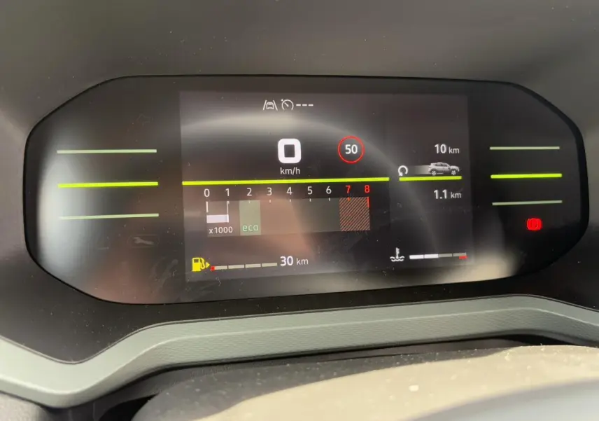 Tableau de bord digital du Dacia Duster 2025 affichant vitesse, régime moteur et autonomie, vue frontale.