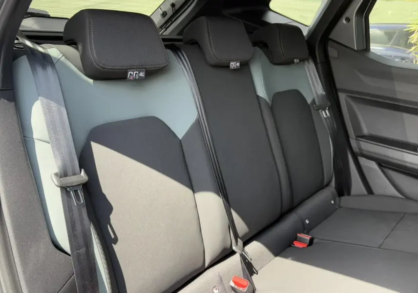 Vue latérale des sièges arrière bicolores gris et noir du Dacia Duster 2025 avec ceintures et appuie-têtes visibles.