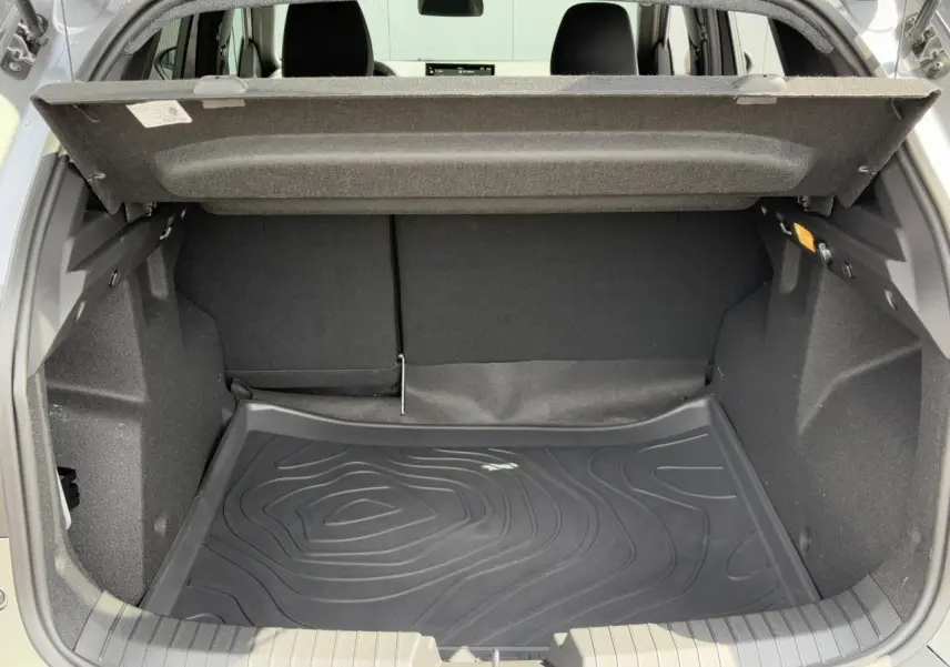 Coffre ouvert du Dacia Duster TCE 4x2 Mild Hybrid 130 gris Schiste, avec tapis de protection noir et intérieur spacieux.