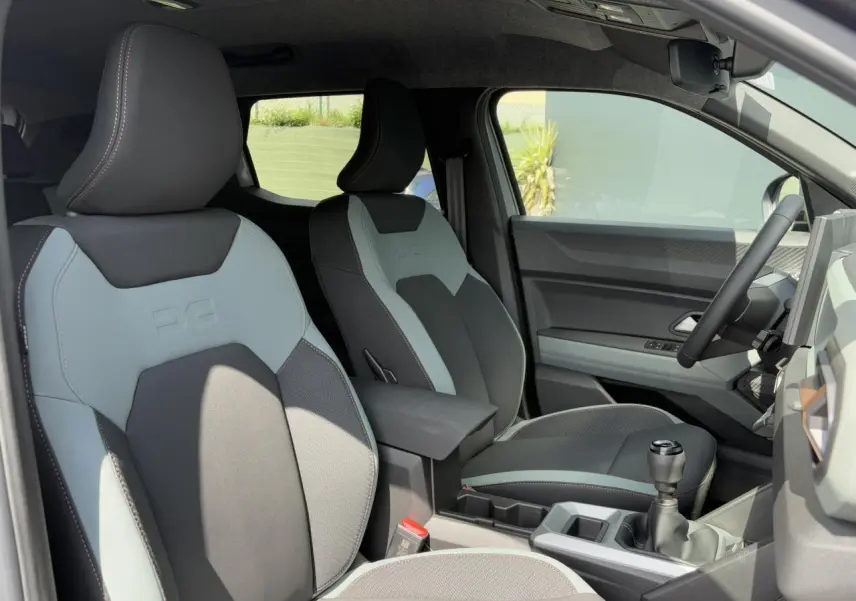 Vue intérieure côté conducteur du Dacia Duster 2025 avec sièges TEP bicolores gris et noir et volant soft feel.