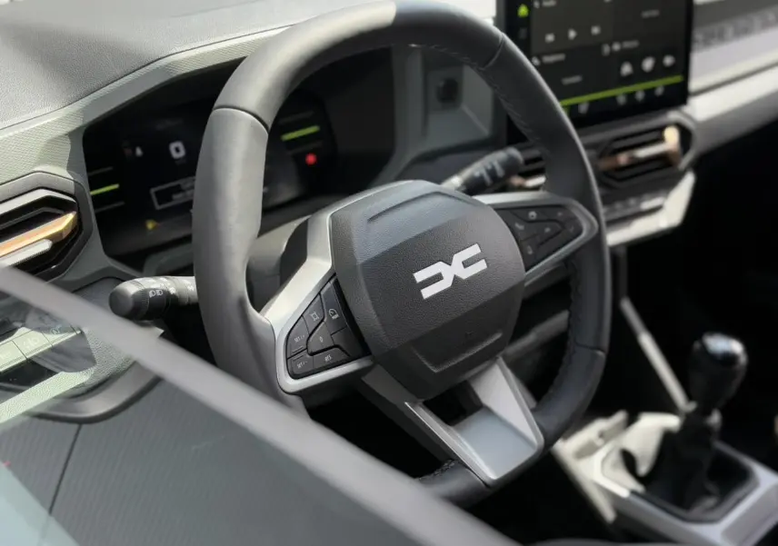 Vue rapprochée du volant et tableau de bord digital du Dacia Duster gris Schiste 2025 avec boîte manuelle.
