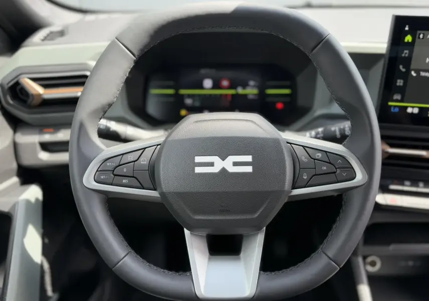 Volant multifonctions noir du Dacia Duster 2025 avec logo Extrême et tableau de bord digital en arrière-plan.