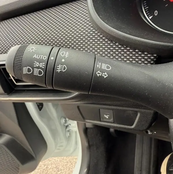 Gros plan sur la commande des phares et clignotants à gauche du volant dans une Dacia Sandero blanche 2021.