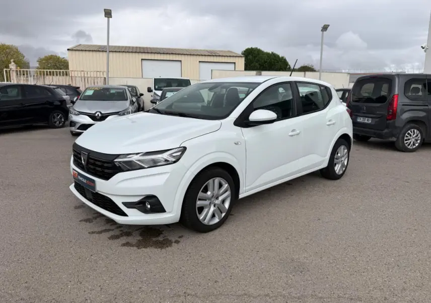 Vue 3/4 avant droite d'une Dacia Sandero blanche 2021 avec phares modernes et jantes alliage visibles.