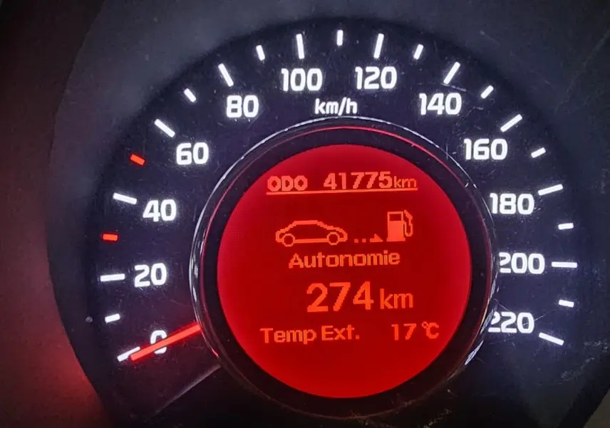 Gros plan sur le compteur de vitesse rouge d'une Kia Rio noire de 2015, affichant 41 775 km et 274 km d'autonomie.