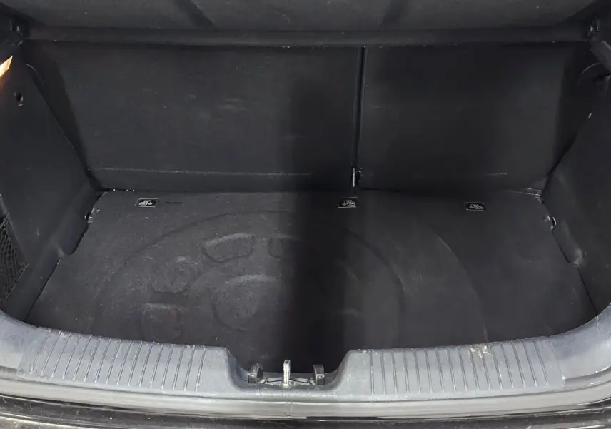 Coffre ouvert d'une KIA RIO III noire de 2015, montrant un espace de rangement vide et propre.