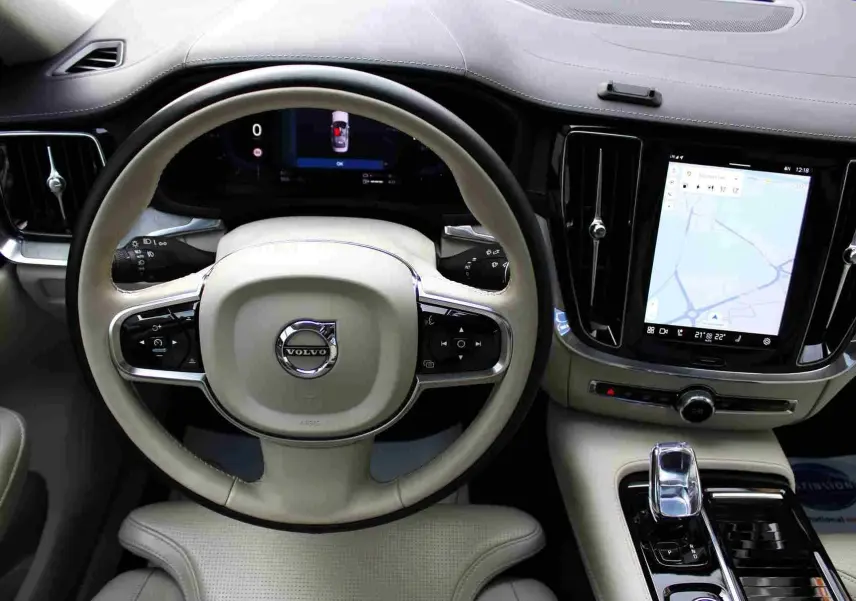 Intérieur clair du Volvo S60 2024 hybride rechargeable, vue centrée sur le volant et l'écran tactile de navigation.