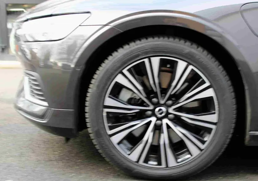 Gros plan sur la roue avant gauche d'une Volvo S60 gris métal 2024, mettant en valeur la jante au design moderne bicolore.