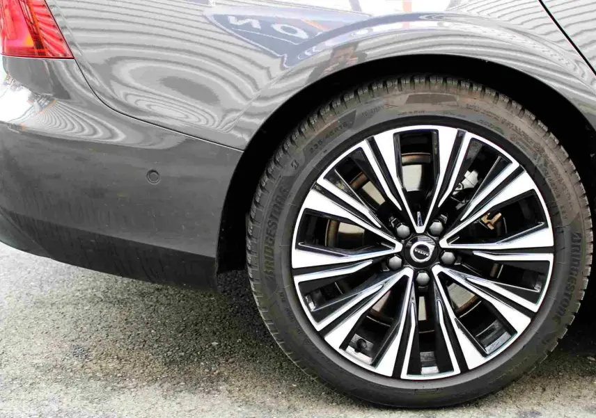 Gros plan sur la roue arrière droite d'une Volvo S60 gris métal 2024, mettant en valeur la jante alliage au design moderne.