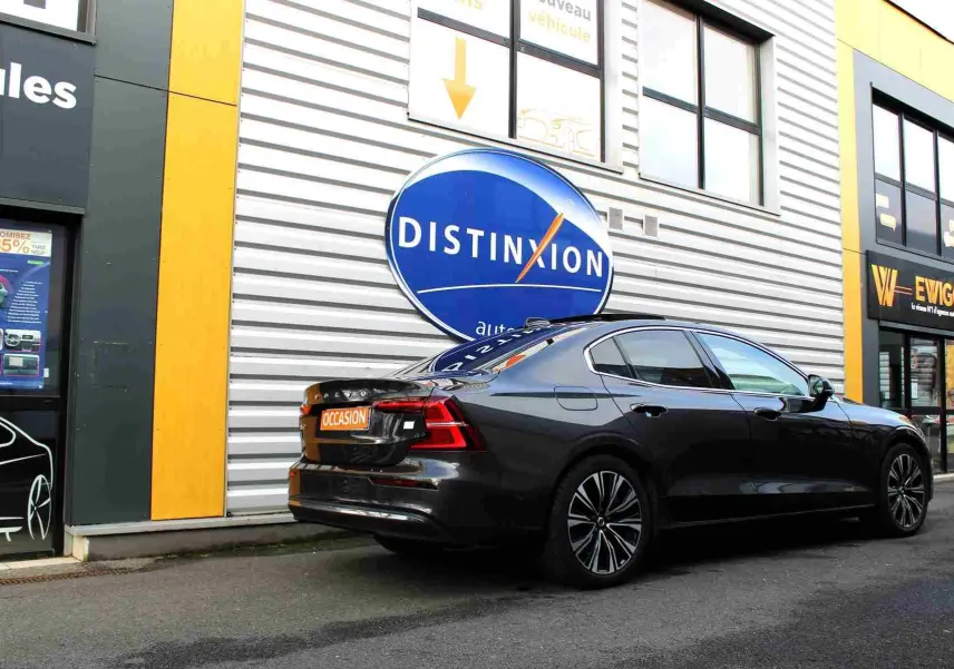 Vue 3/4 arrière droite d'une Volvo S60 T6 AWD hybride rechargeable gris métal, avec jantes stylées et plaque "OCCASION" visible.
