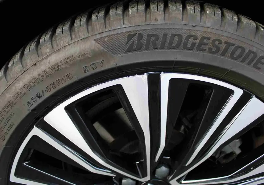 Gros plan sur la jante bicolore noire et chrome d'un pneu Bridgestone du Volvo S60 gris métal 2024 hybride rechargeable.