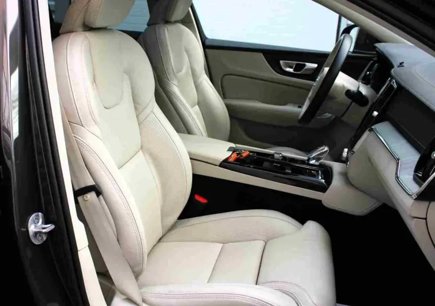 Intérieur clair du Volvo S60 T6 AWD 2024 vu côté conducteur, sièges cuir beige et console centrale moderne.