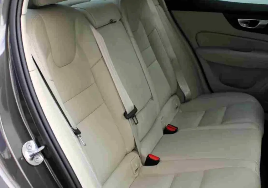 Vue côté gauche des sièges arrière en cuir beige clair d'une Volvo S60 gris métal 2024, détails intérieurs visibles.