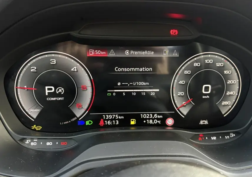 Vue rapprochée du tableau de bord numérique de l'Audi Q2 35 TDI 150 S-Tronic S-Line affichant la consommation et les compteurs.