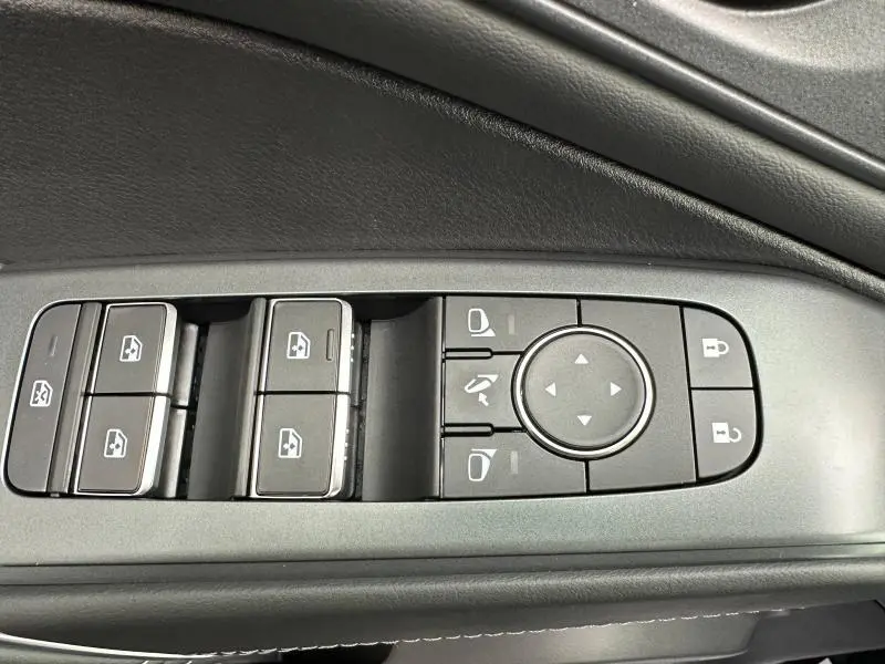 Gros plan sur les commandes de lève-vitres et réglage des rétroviseurs côté conducteur du Nissan Qashqai Hybrid e-POWER blanc nacré 2025.