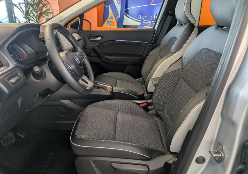 Vue intérieure côté conducteur du Renault Captur gris Highland 2023, montrant les sièges avant et le tableau de bord.
