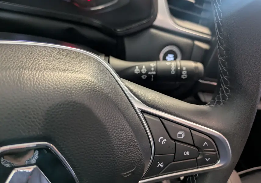 Gros plan sur le volant noir du Renault Captur II Techno 2023, avec commandes multifonctions et surpiqûres visibles.