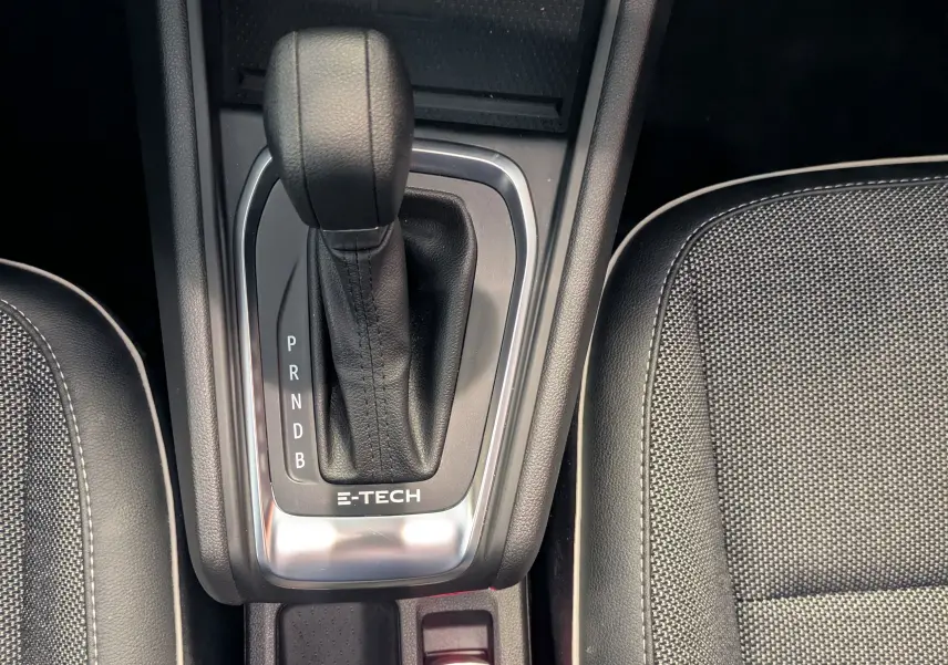 Vue plongeante sur la console centrale du Renault Captur gris Highland, avec levier de vitesse automatique E-TECH et sièges noirs.
