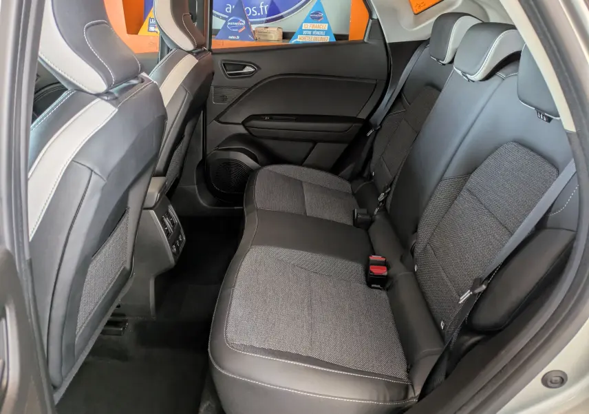 Vue intérieure arrière côté droit du Renault Captur II Techno 2023, sièges tissu et cuir noir avec surpiqûres blanches.