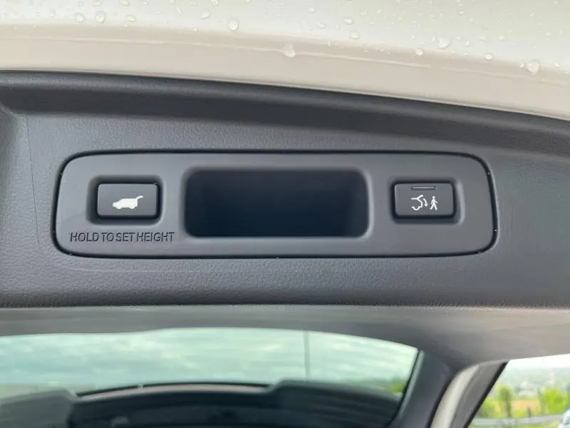 Gros plan sur les boutons de commande du hayon électrique du Honda CR-V blanc nacré, visibles sur la partie intérieure du coffre.
