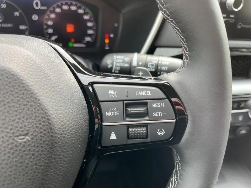Gros plan sur les commandes multifonctions du volant cuir noir du Honda CR-V blanc platine nacrée 2024, côté droit.