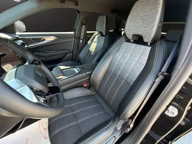 Vue intérieure du Renault Austral 2025 noir, focus sur la console centrale avec zone de recharge par induction et accoudoir cuir.