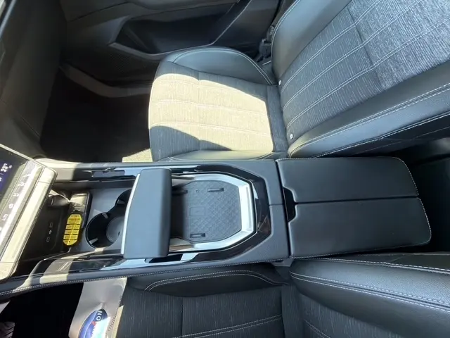 Vue intérieure centrée sur la console centrale et les sièges avant en tissu noir avec surpiqûres blanches du Renault Austral 2025.