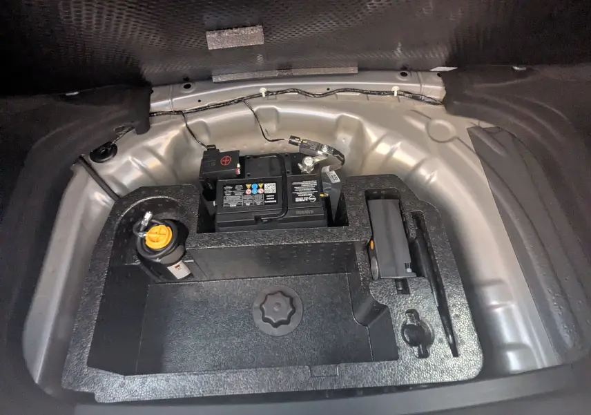 Vue plongeante sur le compartiment batterie et outils dans le coffre du MG3 1.5L Hybrid+ gris Hampstead.