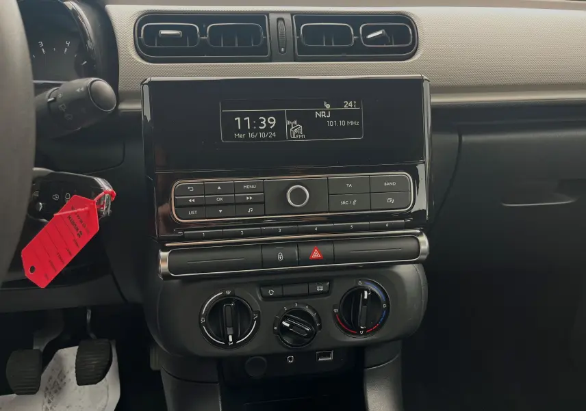 Tableau de bord de Citroën C3 blanc 2017, vue centrale sur la console avec écran radio et commandes manuelles de climatisation.