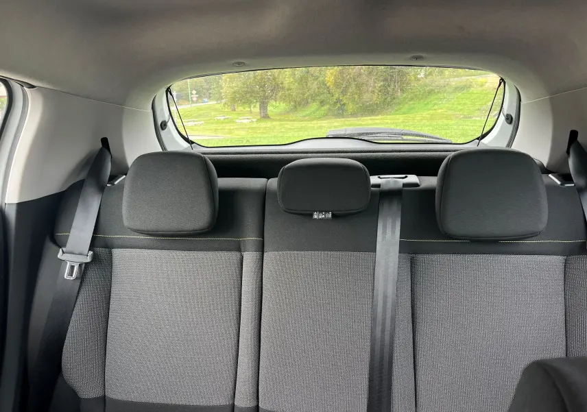 Vue intérieure arrière des sièges en tissu gris noir d'une Citroën C3 blanche de 2017 avec ceintures visibles.