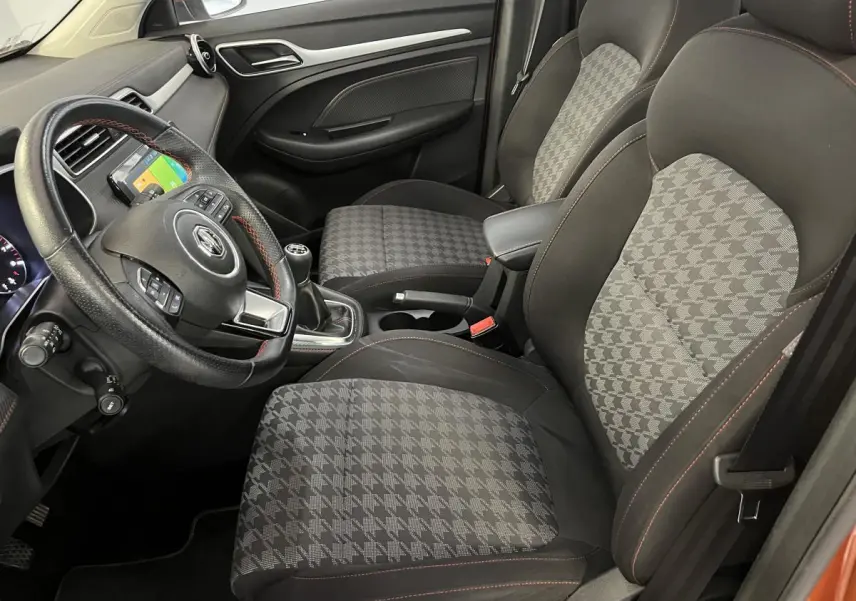 Intérieur avant droit du MG ZS 2022, sièges tissu à motif pied-de-poule et volant cuir avec surpiqûres rouges.