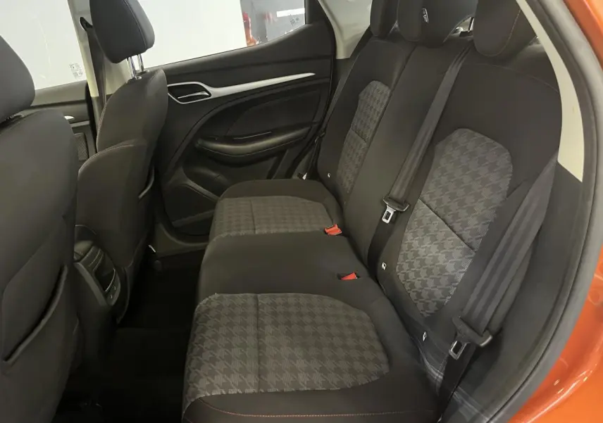 Vue intérieure côté droit sur la banquette arrière en tissu noir et gris du MG ZS orange 2022 avec ceintures de sécurité visibles.