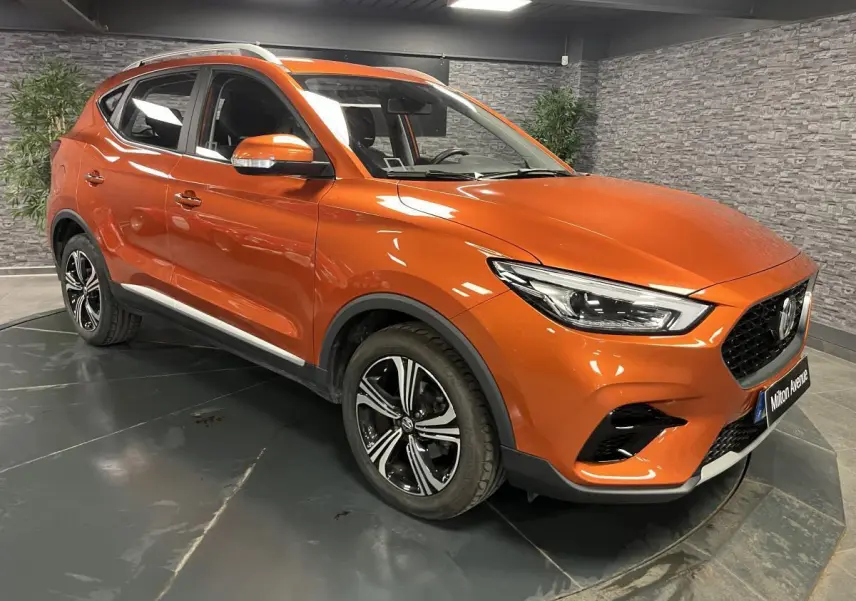 MG ZS orange métallisé en 3/4 avant droit, avec jantes alliage noires et calandre noire distinctive.