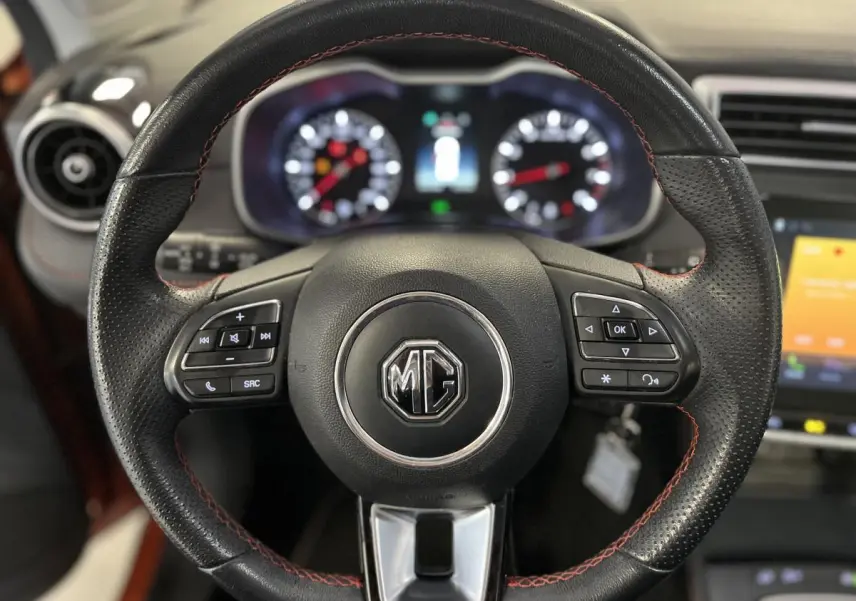 Volant en cuir noir avec surpiqûres rouges du MG ZS 2022, vue frontale sur le tableau de bord et l'écran tactile.