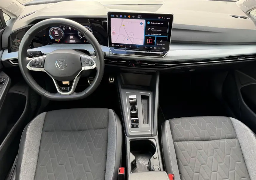 Vue intérieure frontale du poste de conduite de la Volkswagen Golf 2024 avec tableau de bord digital et écran tactile central.