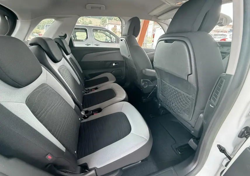 Vue intérieure arrière côté droit du Citroën C4 Picasso blanc, montrant les sièges tissu bi-tons gris et noir.