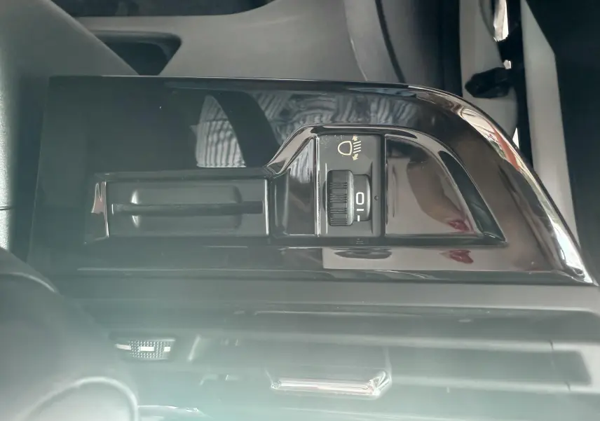 Gros plan sur le réglage de hauteur des phares dans l'habitacle d'une Citroën C4 Picasso blanc de 2014.