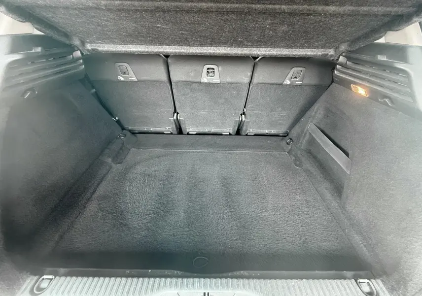 Coffre spacieux vu de l'intérieur arrière d'une Citroën C4 Picasso 2014 blanche, avec sièges arrière rabattables.